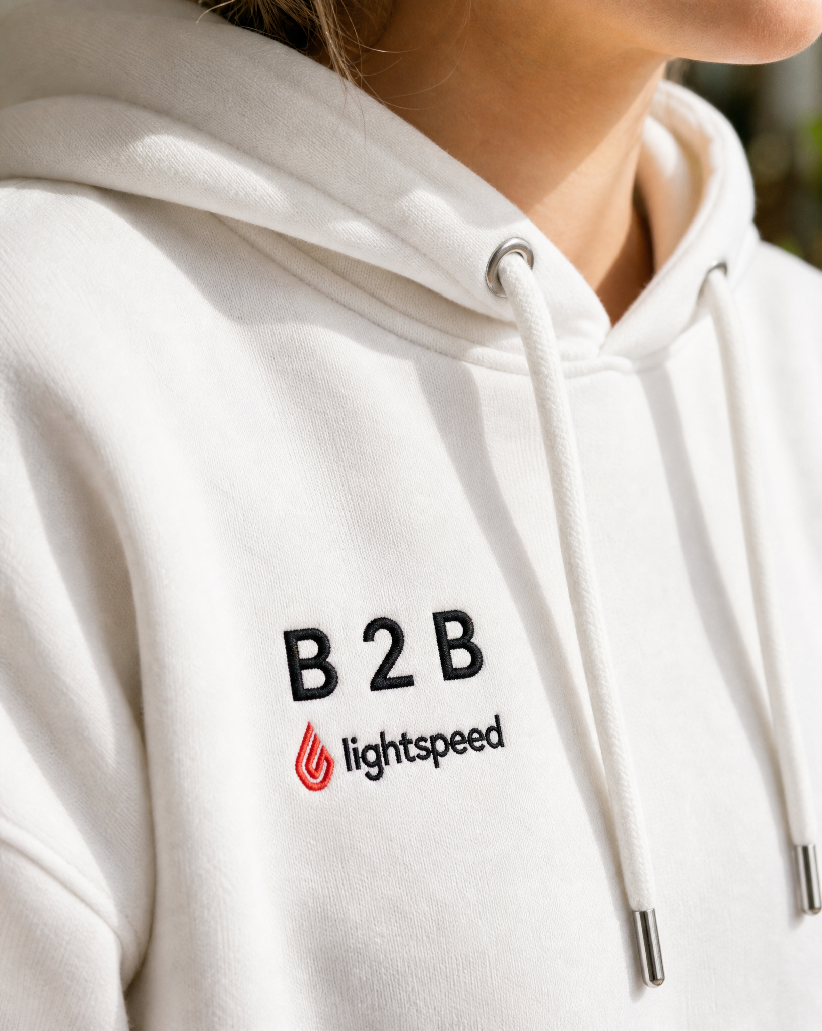 Close-up of the embroidered B2B × Lightspeed logo on the white hoodie