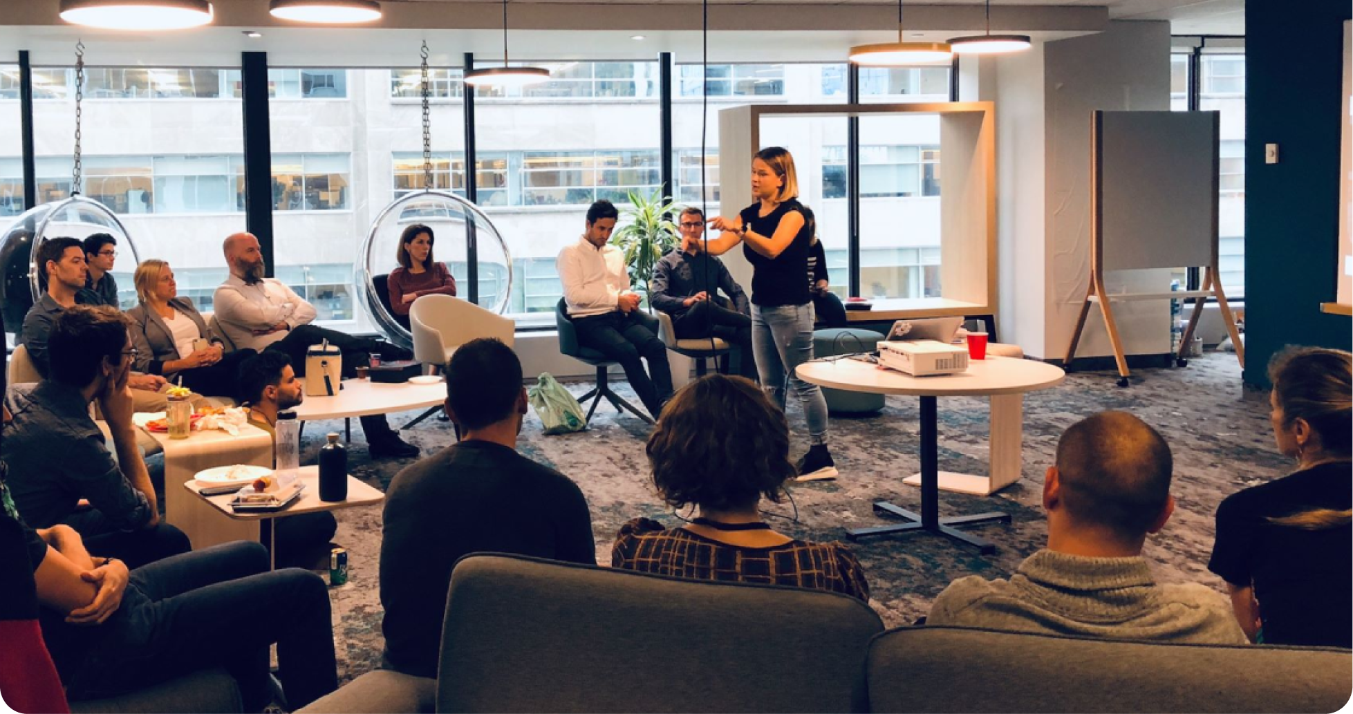 Olga presenting to a seated audience in an office lounge during a company technology summit