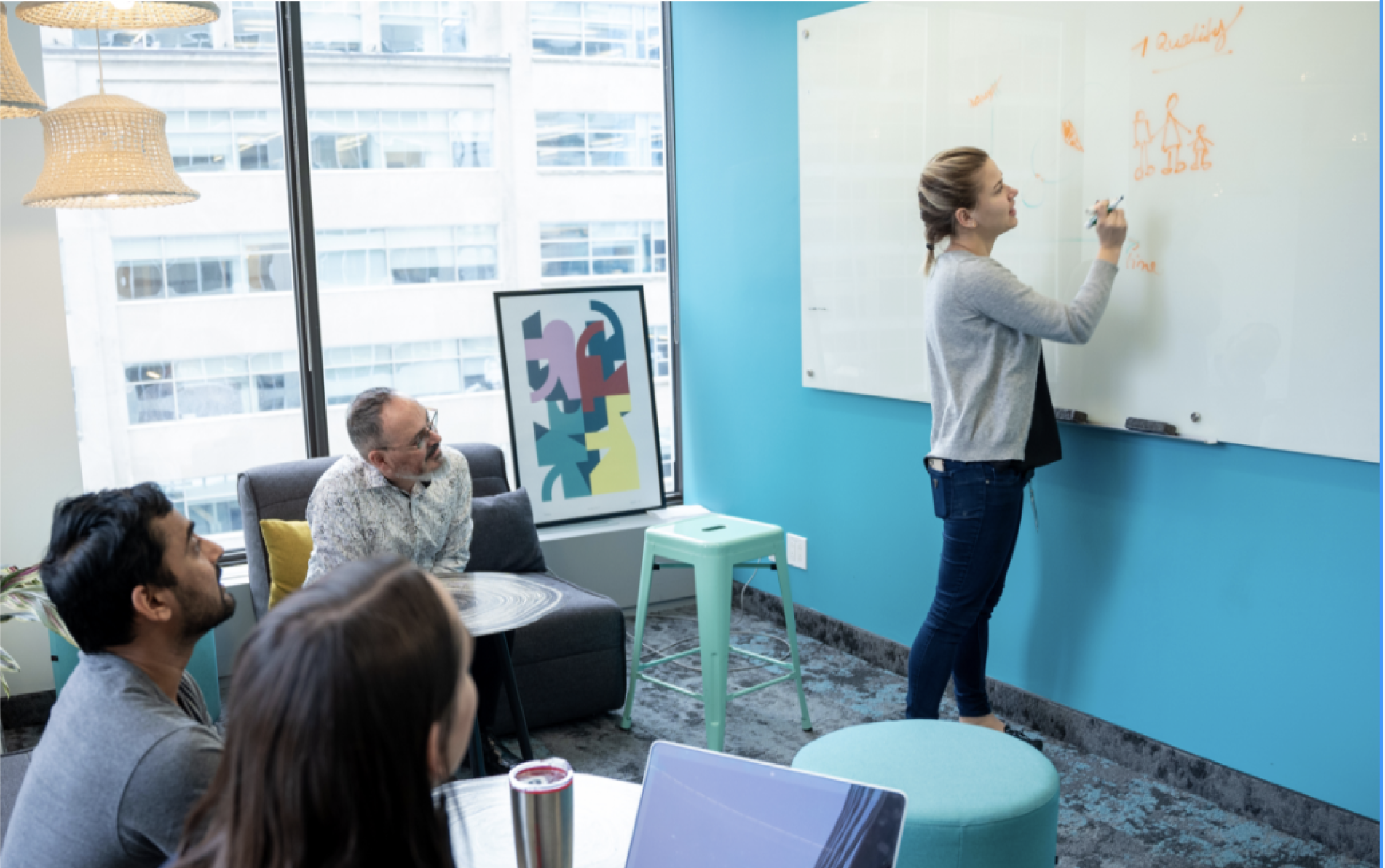 Olga sketching on a glass whiteboard while colleagues watch during a workshop